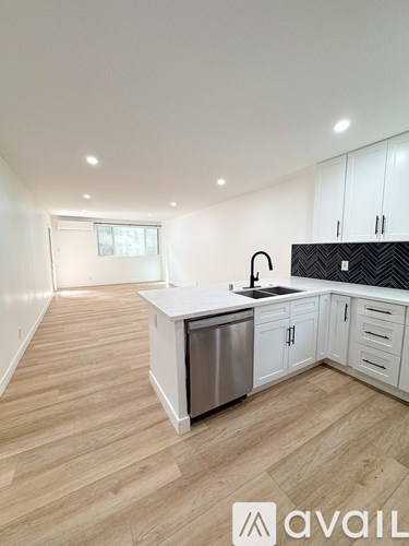 A kitchen with white cabinets and a wooden floor.
