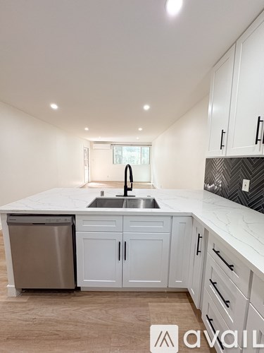 A kitchen with white cabinets and a marble countertop.
