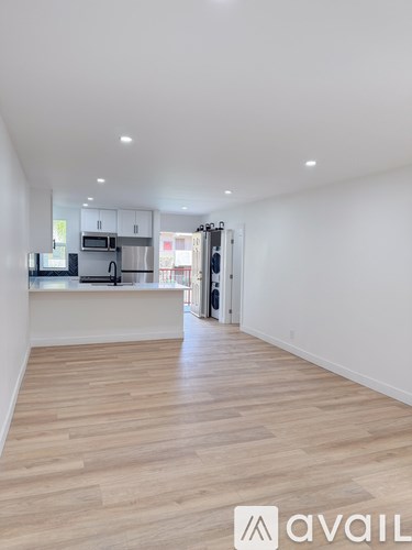 A spacious kitchen with white cabinets and a wooden floor.