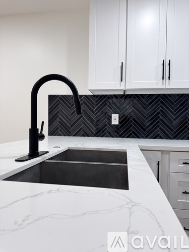 A kitchen with a sink and a black faucet.