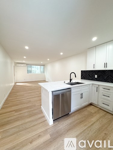A kitchen with white cabinets and a wooden floor.