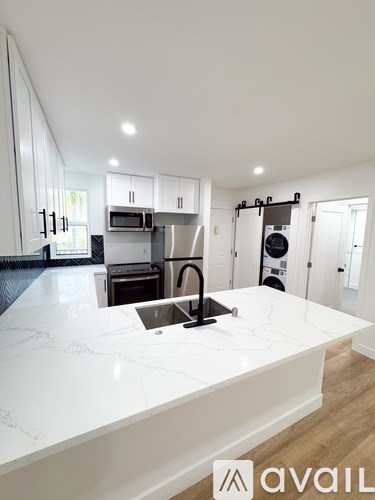 A modern kitchen with a white marble countertop and stainless steel appliances.