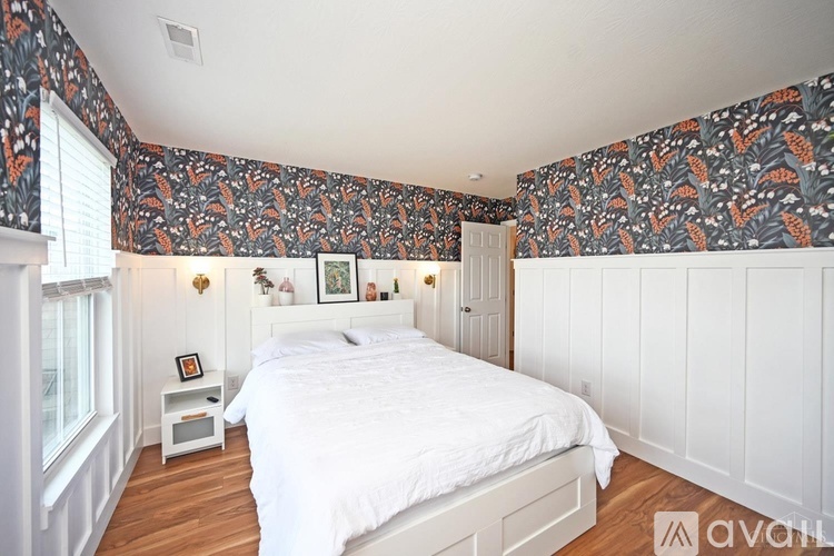 A bedroom with a white bed and a patterned wallpaper.