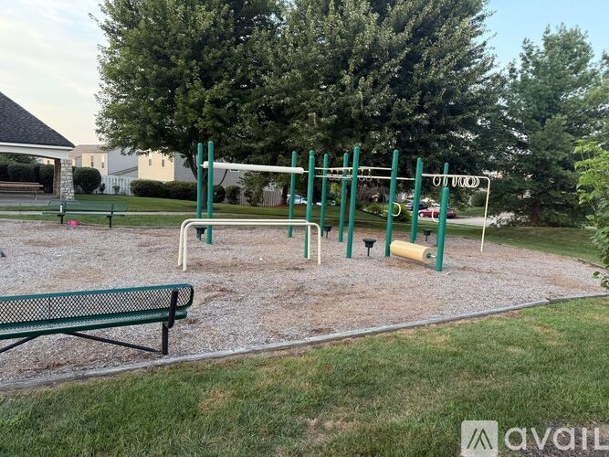 A park with a green bench and a playground with a slide.