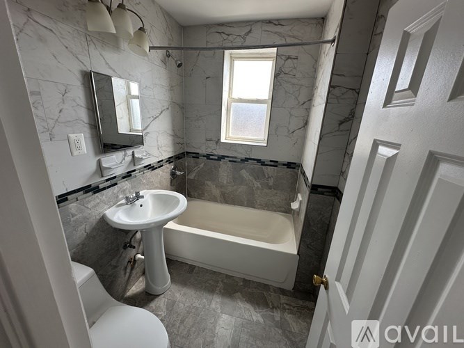 A bathroom with a marble wall and a white sink.