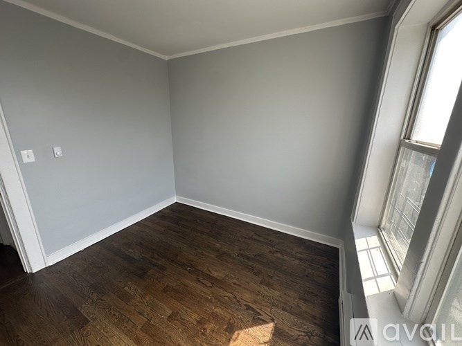 A room with wooden flooring and a window on the right side.