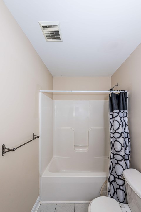 A white toilet sits next to a bathtub in a bathroom.
