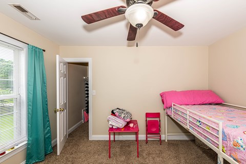 A bedroom with a bed, chair, and window.
