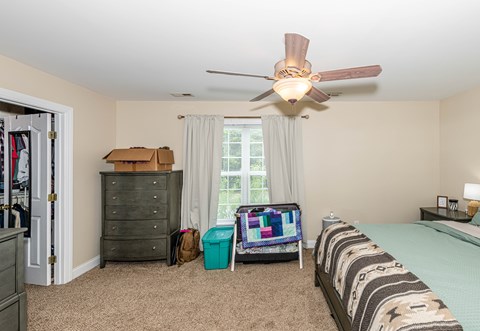 A room with a ceiling fan and a bed.