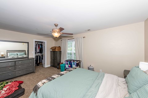 A bedroom with a bed, dresser, and a ceiling fan.