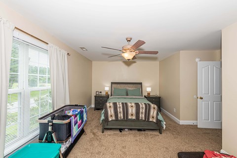 A bedroom with a bed, dresser, and window.