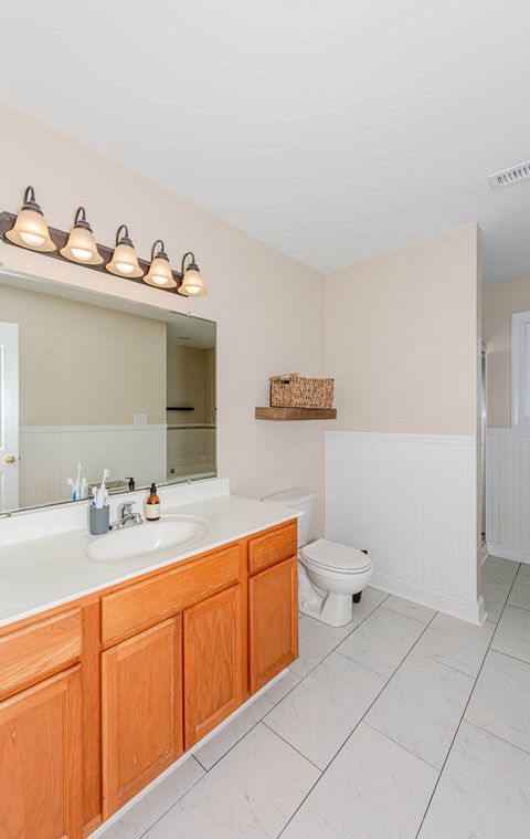 A bathroom with a toilet, sink, and mirror.