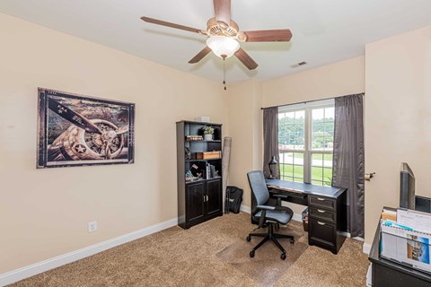 A room with a ceiling fan and a painting on the wall.