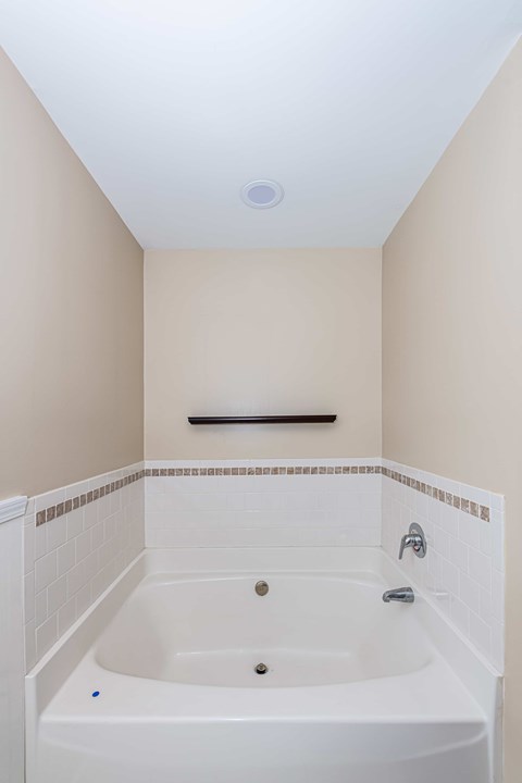 A white bathtub with a shower head and faucet.