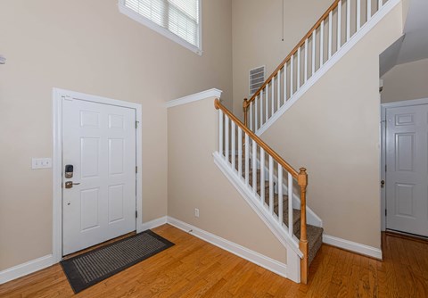A white door is on the left of a staircase.