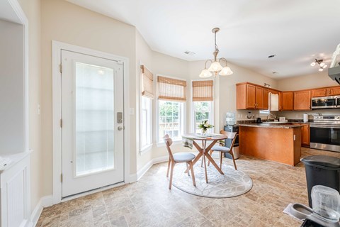 A kitchen with a dining table and chairs in the middle of the room.