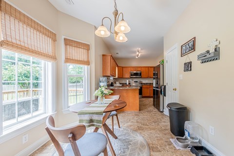 A kitchen with a table and chairs in front of a window.