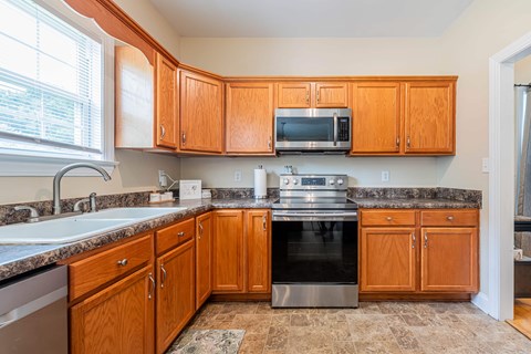A kitchen with wooden cabinets and a granite countertop.