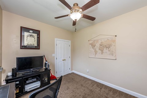 A living room with a ceiling fan and a world map on the wall.