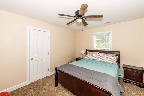 A bedroom with a bed, nightstand, and window.