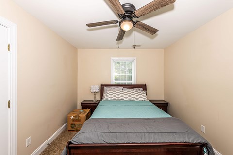 A bedroom with a bed, nightstand, and window.