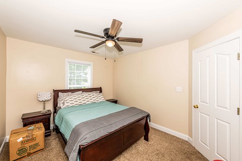 A bedroom with a bed, nightstand, and a ceiling fan.