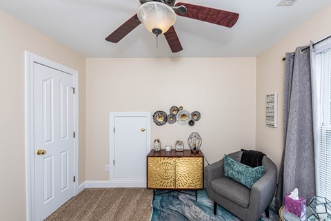 A room with a ceiling fan and a chair with a cushion.