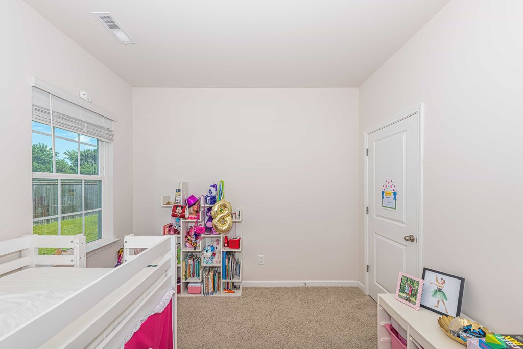 A white bedroom with a white bed and a white dresser.
