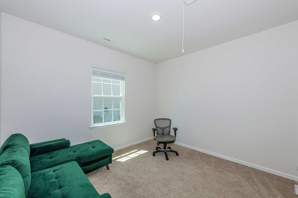 A room with a green couch and a chair.