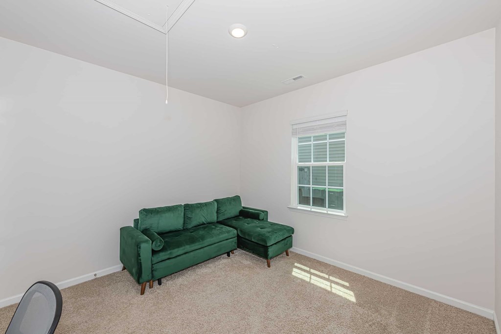 A green couch in a room with a window.