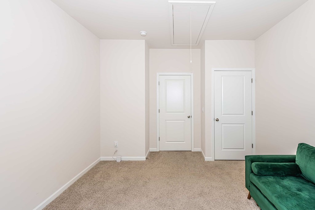 A room with a green couch and two white doors.