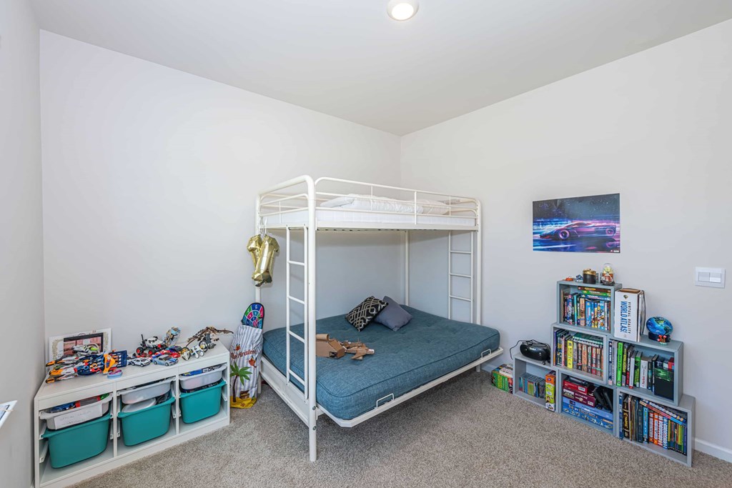 A white bunk bed with a blue mattress is in a room with a car poster on the wall.