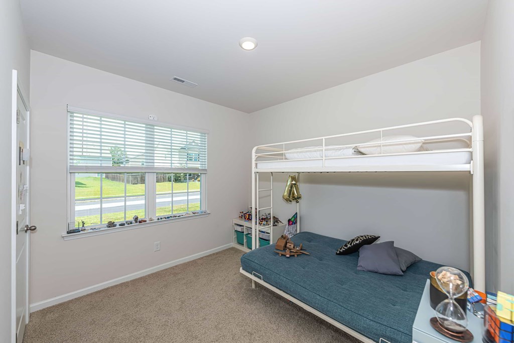 A bedroom with a bunk bed and a window with blinds.