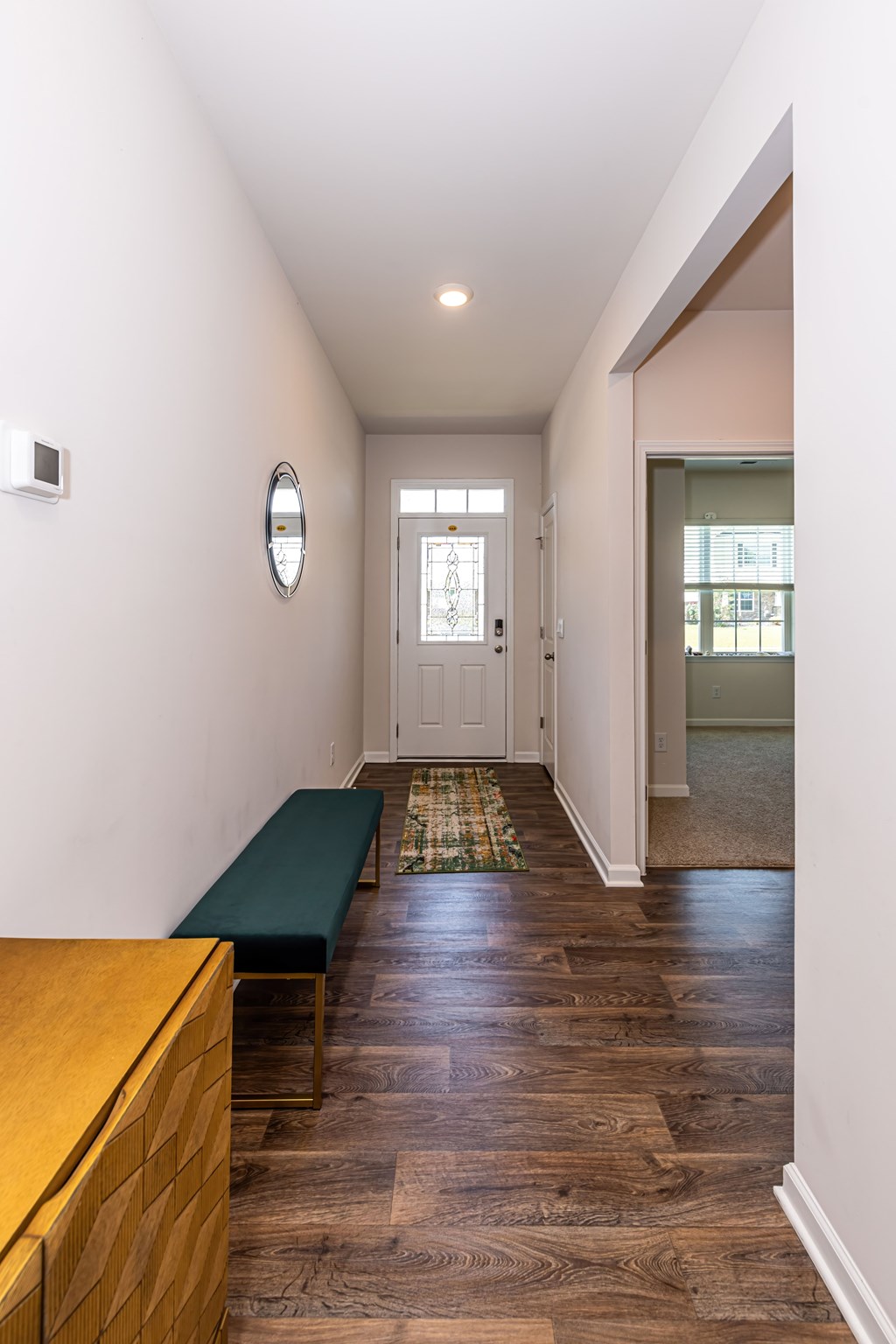 A hallway with a bench and a mirror on the wall.