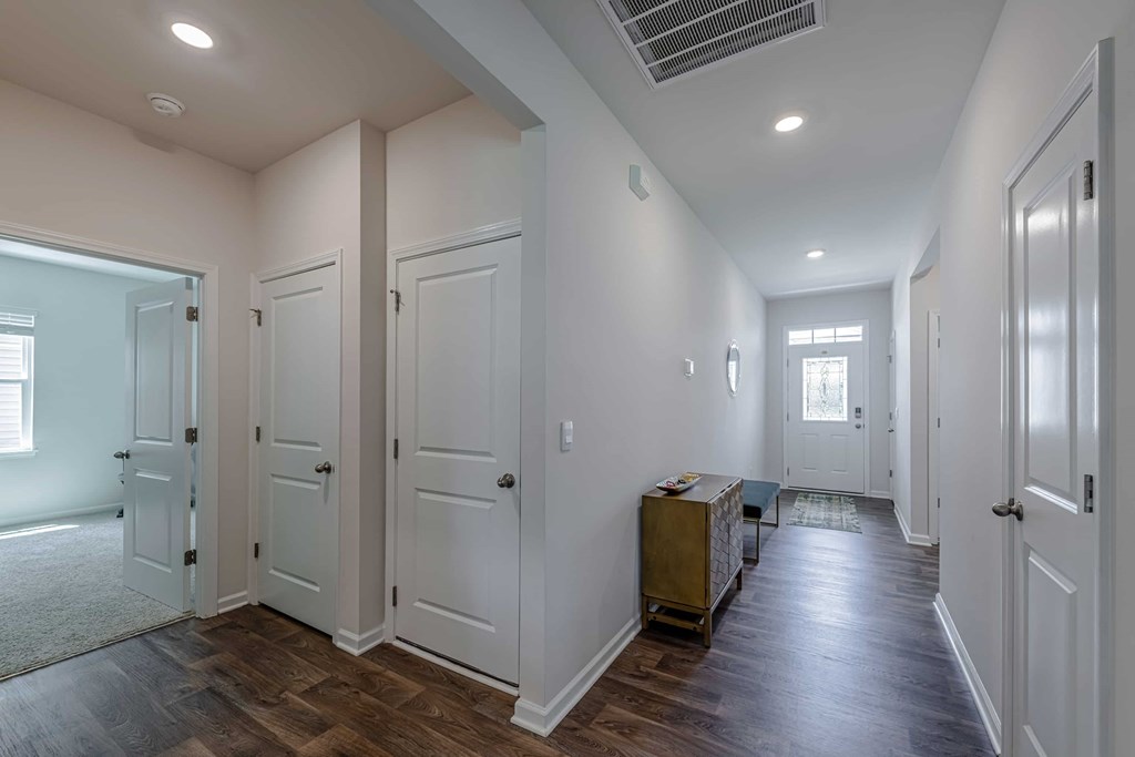 A long hallway with white doors and a brown trunk.