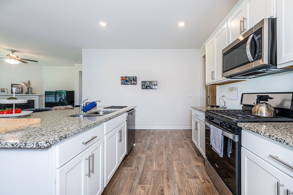 A kitchen with white cabinets and a granite countertop.