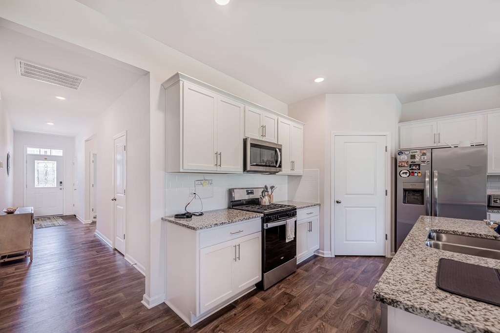A kitchen with white cabinets and a granite counter top.