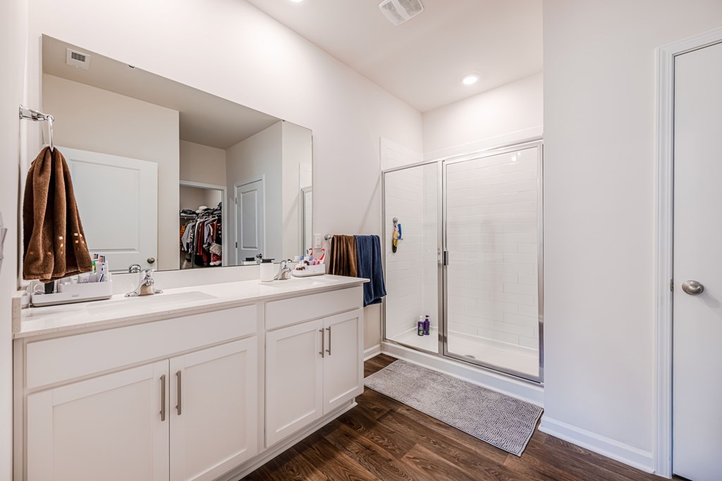 A bathroom with a white vanity and a walk-in shower.