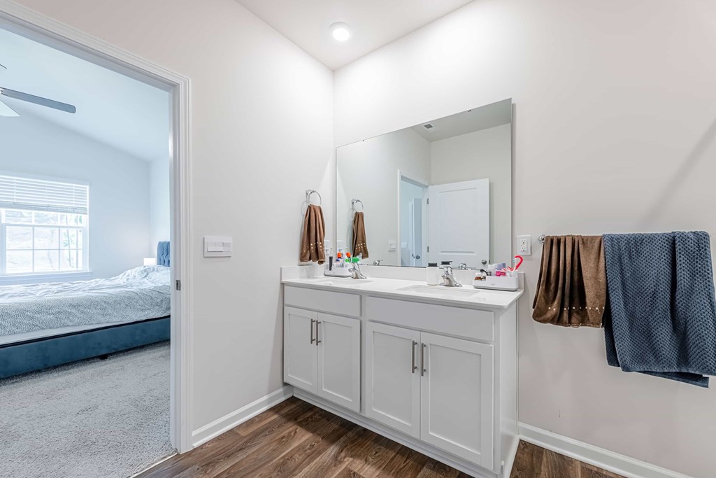 A bathroom with a white cabinet and a mirror above it.