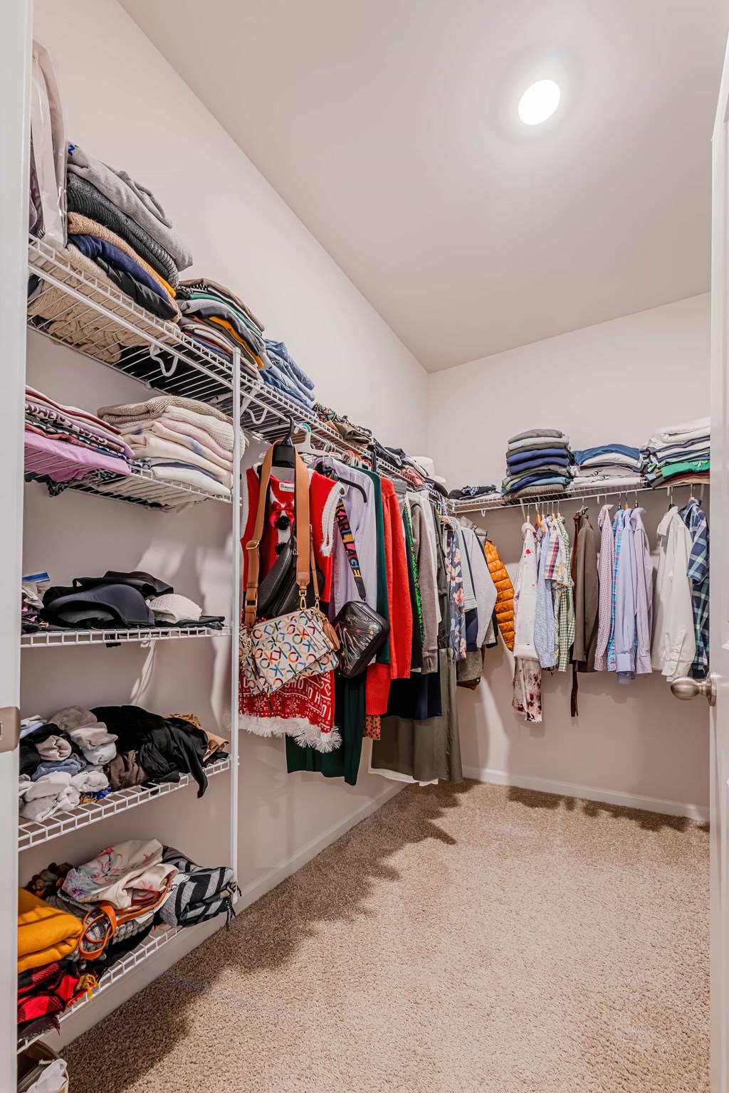A white closet with clothes and shoes on shelves.