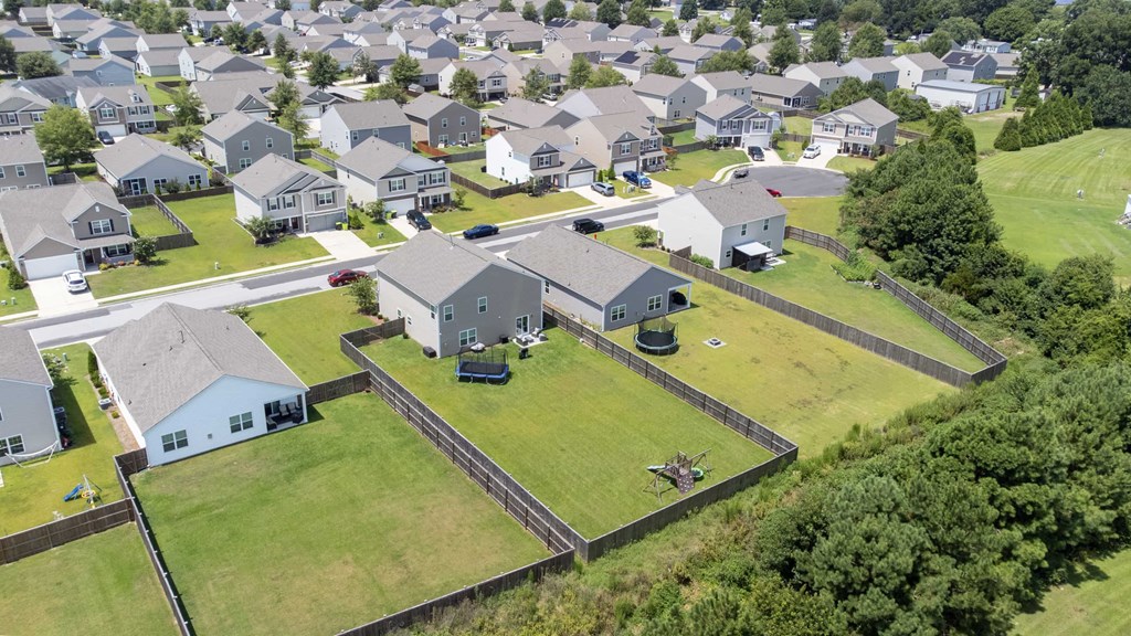 A large grassy area with a fence and a house in the middle.