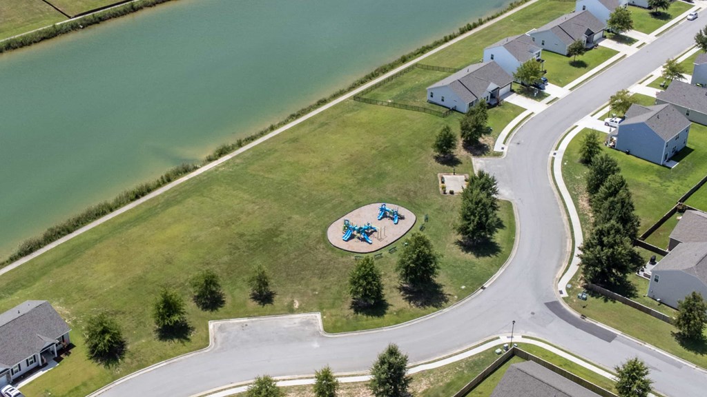 A playground with a blue and white slide is surrounded by houses.