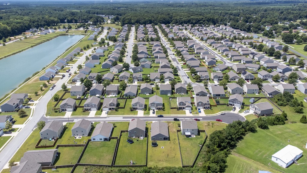 A bird's eye view of a residential neighborhood with houses and a lake.