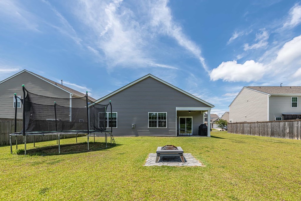 A backyard with a trampoline and a fire pit.