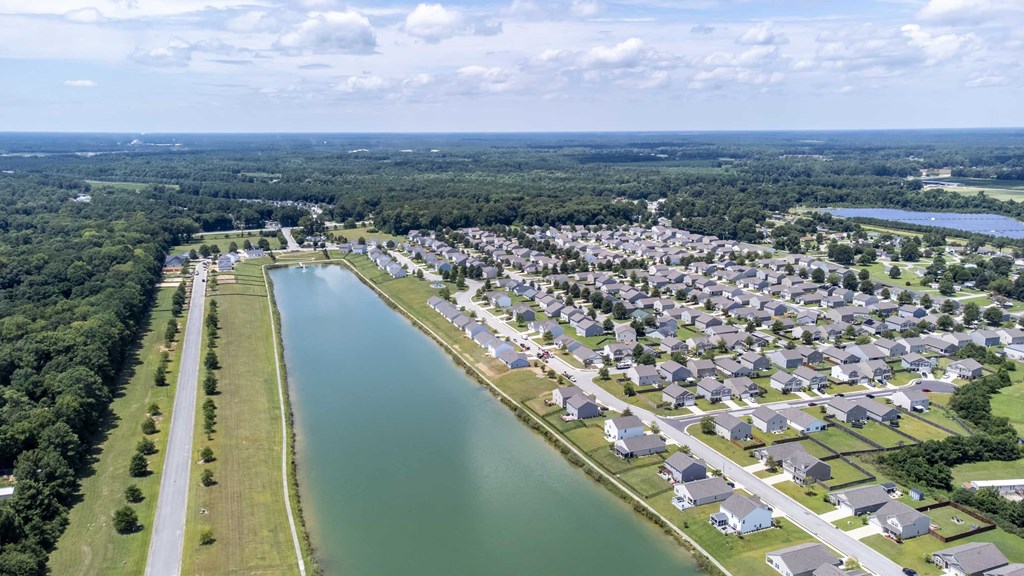 A bird's eye view of a residential area with a lake running through it.
