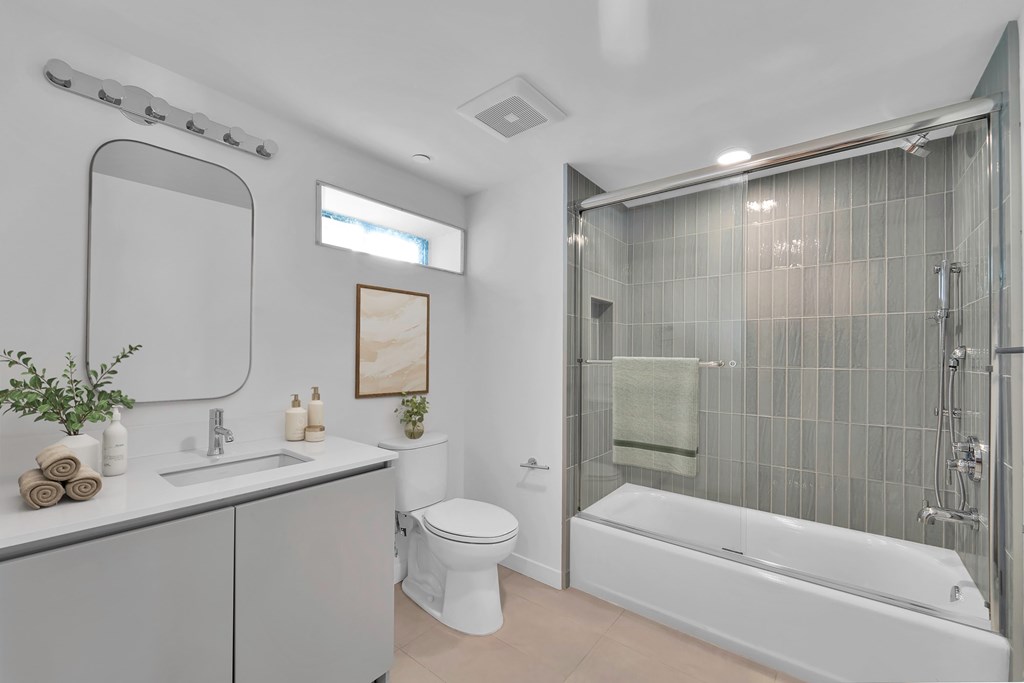 A modern bathroom with a white toilet, sink, and bathtub.