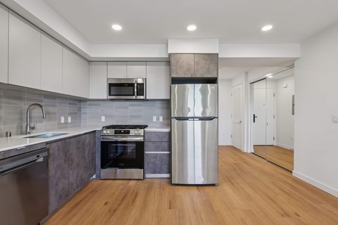 A modern kitchen with a stainless steel refrigerator and wooden floors.