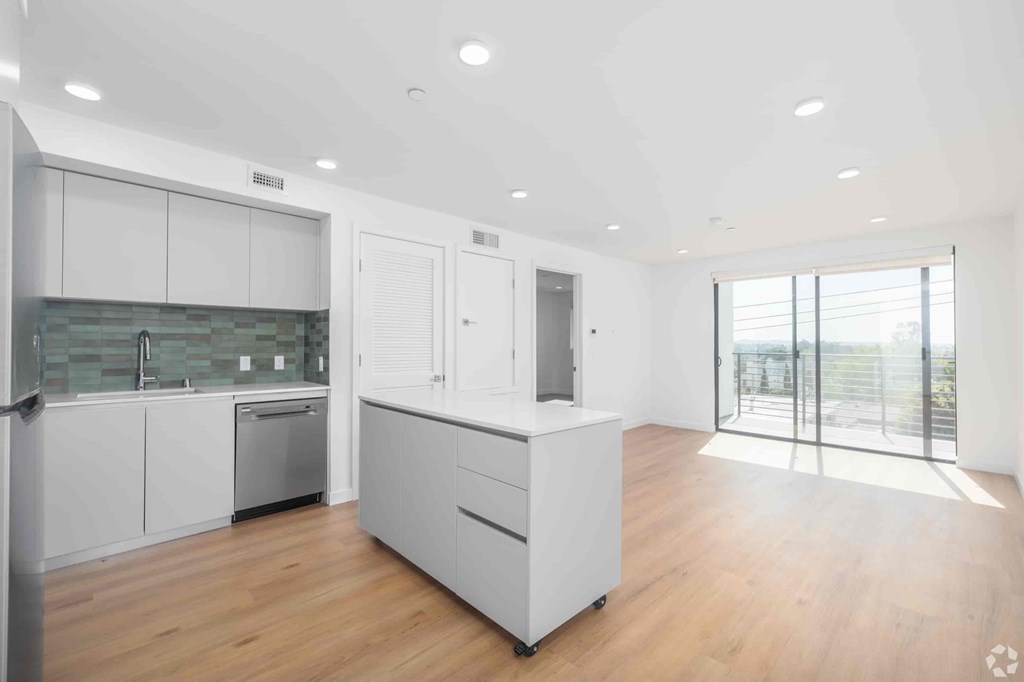 A modern kitchen with white cabinets and a wooden floor.