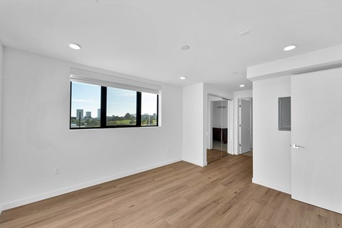 A spacious room with wooden floors and a large window.