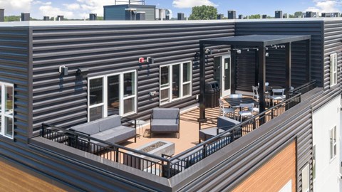 A balcony with a table and chairs is on the roof of a building.